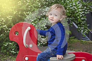 Cute little child boy having fun playing with colorful wooden toys outdoors in the park, beautiful spring sunny day in children