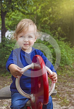 Cute little child boy having fun playing with colorful wooden toys outdoors in the park, beautiful spring sunny day in children
