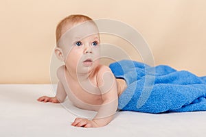 Little baby boy is relaxing and smiling happily on the bed after bath