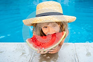 Cute little child boy in the swimming pool eating watermelon. Enjoy eating tropical fruit. Summer kids concept. Happy