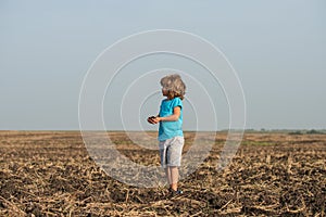 Cute little child farmer working on field. Ecology planting on land. Black soil on child hand. Earth day concept. Summer