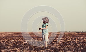 Cute little child farmer working on field. Ecology planting on land. Black soil on child hand. Earth day concept. Summer