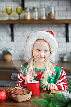 Cute little child girl eating sweet cookies and drinking hot cocoa