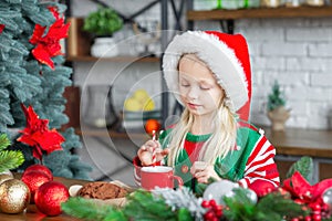 Cute little child girl eating sweet cookies and drinking hot cocoa