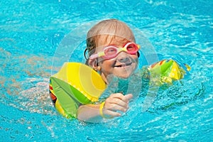 Cute little child girl having fun in swimming pool. Summer holiday and happy carefree childhood concept