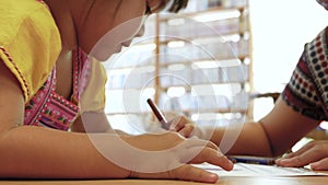 Cute little child girl and her mother colouring with crayons in the paper together in living room at home.