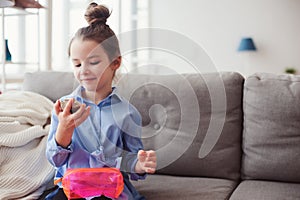 cute little child girl with mirror and cosmetic bag checking hairstyle at home