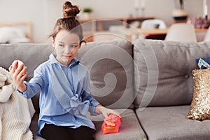 Cute little child girl with mirror and cosmetic bag checking hairstyle at home