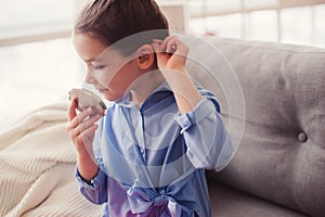 Cute little child girl with mirror and cosmetic bag checking hairstyle at home