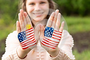 Cute little child girl with painted hands in American flag color, focus on hands. USA celebrate 4th of July