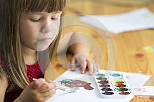 Cute little child girl painting with paintbrush and colorful paints