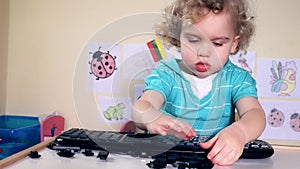 Cute little child girl playing with computer keyboard keys on table