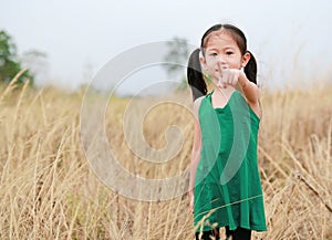 Cute little child girl pointing at camera in summer field outdoor