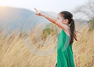 Cute little child girl pointing up in summer field outdoor. Freedom style