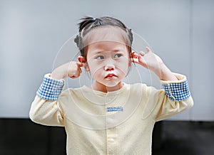 Cute little child girl shutting down her ears, holding her hands covers ears not to hear