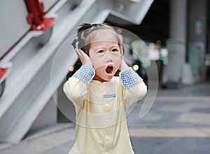 Cute little child girl shutting down her ears, holding her hands covers ears not to hear