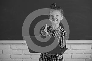 Cute little child girl using laptop computer, kid studying through online e-learning. Little funny system administrator.