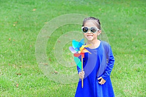 Cute little child girl with wind turbine in the garden.
