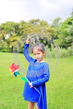 Cute little child girl with wind turbine in the garden.