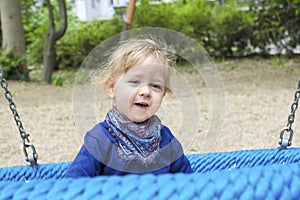 Cute little child having fun on a colorful swing outdoor in the park. Beautiful spring day in children playground