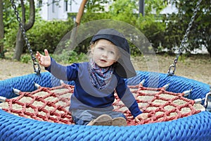 Cute little child having fun on a colorful swing outdoor in the park. Beautiful spring day in children playground