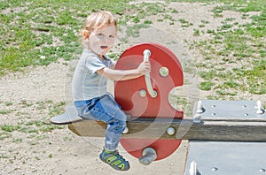Cute little child having fun playing with colorful wooden toys in the park, beautiful summer sunny day in children playground
