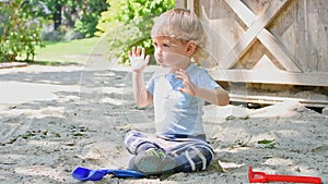 Cute little child having fun playing with sand and colorful toys in the park, beautiful summer sunny day in children playground