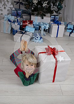 cute little child is lying on floor near large gift box, dreaming of surprise