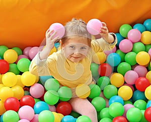 Cute little child playing in ball pit at amusement park