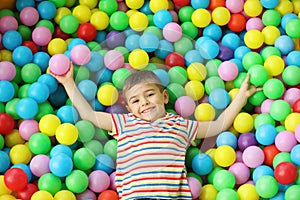 Cute little child playing in ball pit at indoor park