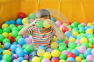 Cute little child playing in ball pit at indoor park