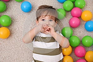 Cute little child playing with balls on floor