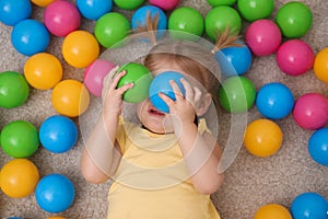 Cute little child playing with balls on floor
