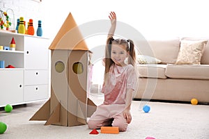 Cute little child playing with cardboard rocket