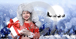 Cute little child and Santa Claus flying in his sleigh against moon sky on background. Christmas celebration