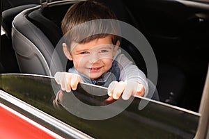 Cute little child sitting in safety seat inside car