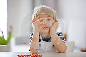 Cute little child, toddler boy, eating alfa omega 3 child supplement vitamin pills at home