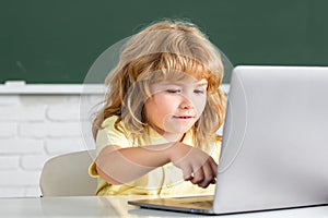 Cute little child using laptop computer, kid boy studying through online e-learning. Little funny system administrator