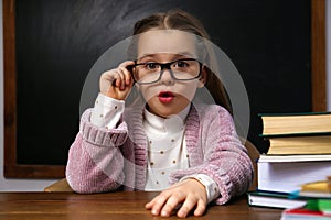 Cute little child wearing glasses at desk. First time at school