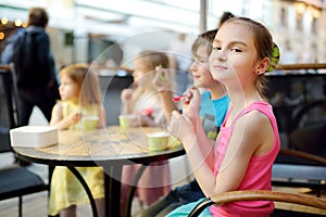 Cute little children eating tasty fresh ice cream in outdoor cafe. Kids eating sweets