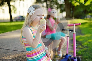 Cute little children eating tasty fresh ice cream in sunny summer park. Kids eating sweets
