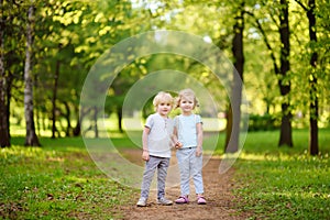 Cute little children playing together and holding hands in sunny summer park