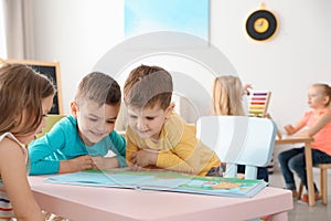 Cute little children reading book at table. Learning and playing