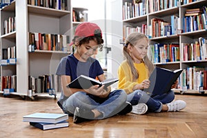 Cute little children reading books on floor