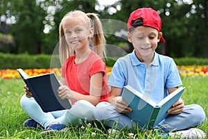 Cute little children reading books on green grass