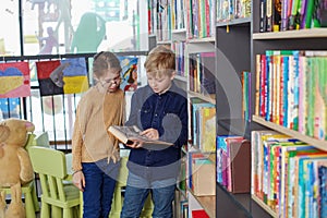 Cute little children reading books in library. Concept of studying, back to school, friends and education