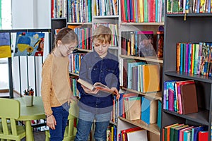 Cute little children reading books in library. Concept of studying, back to school and friends