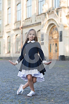 Cute little dance girl in school uniform make curtsy outdoors, dancing