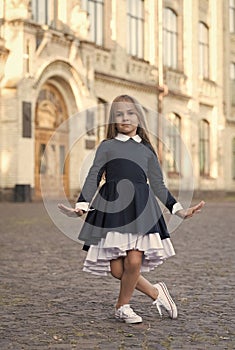 Cute little dance girl in school uniform make curtsy outdoors, dancing