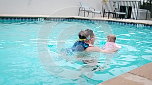 Cute little daughter and his father swimming in the pool. The father is holding his daughter in his hands and embracing